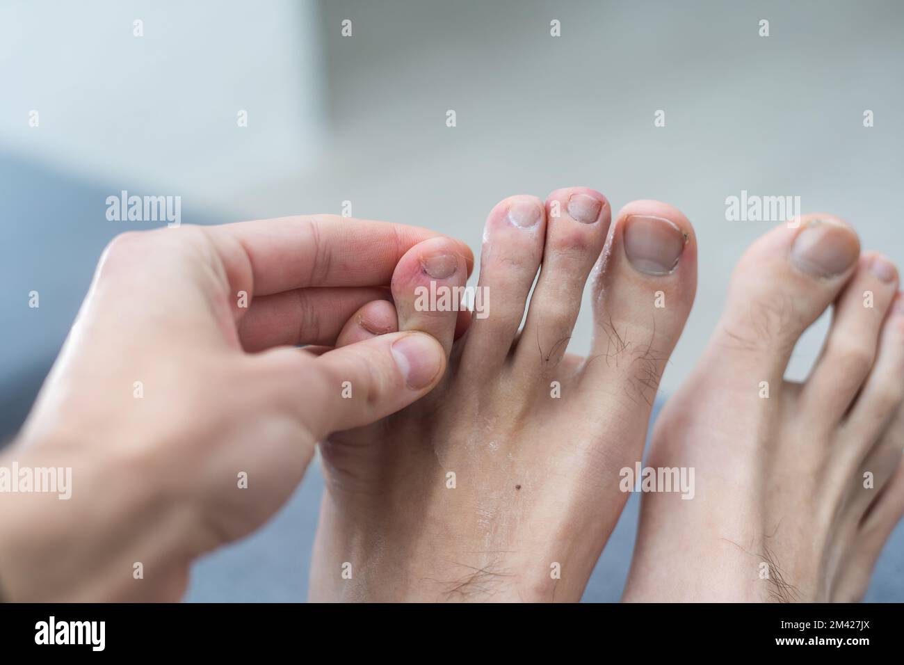 The foot and long nail toes on white concrete background. Long nails and dirty may cause fungal. Stock Photo