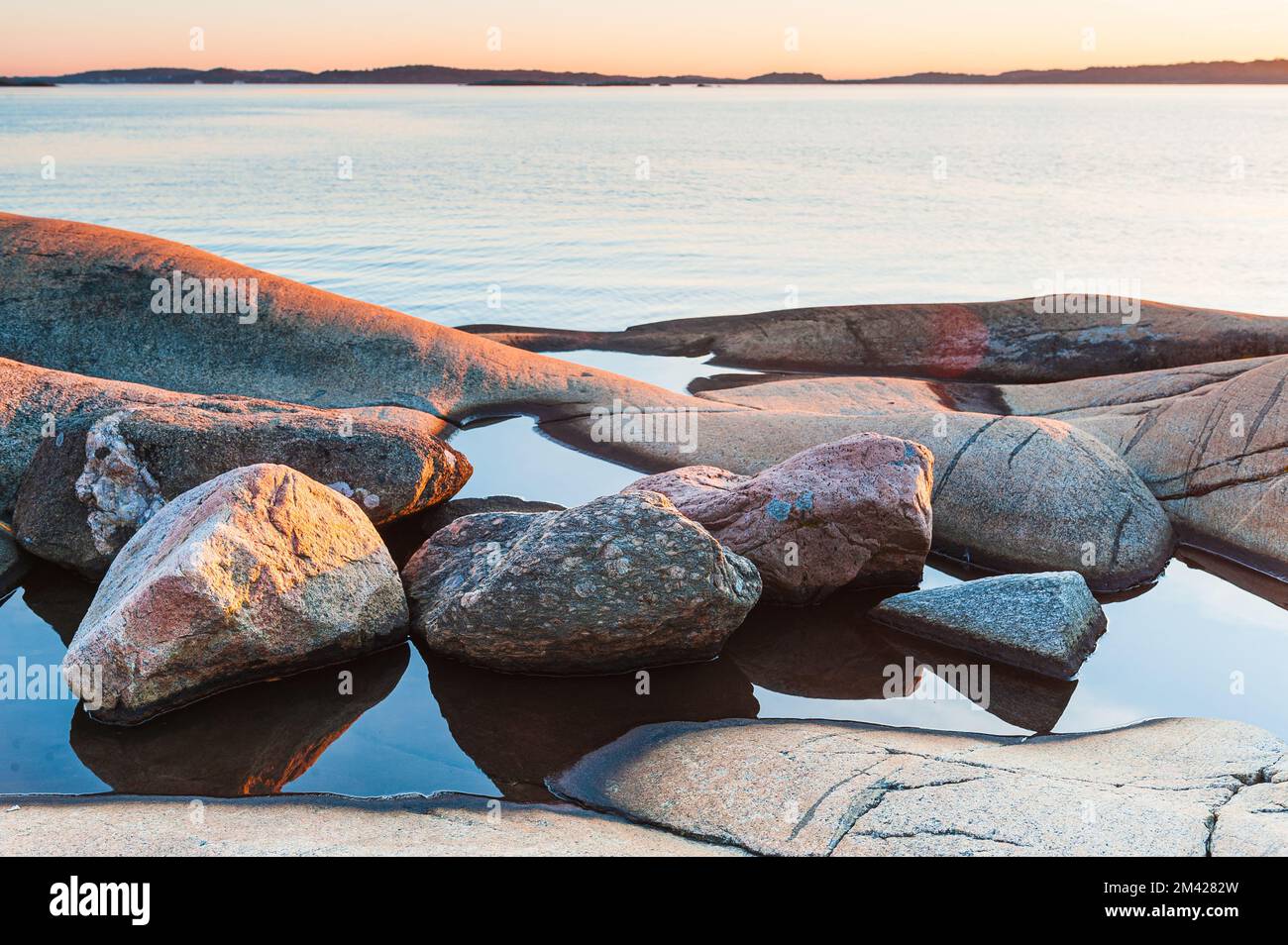 Stones lying in water in front of sea Stock Photo