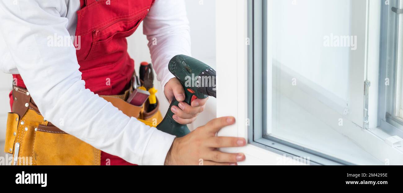 master with a screwdriver sets fittings on the window Stock Photo