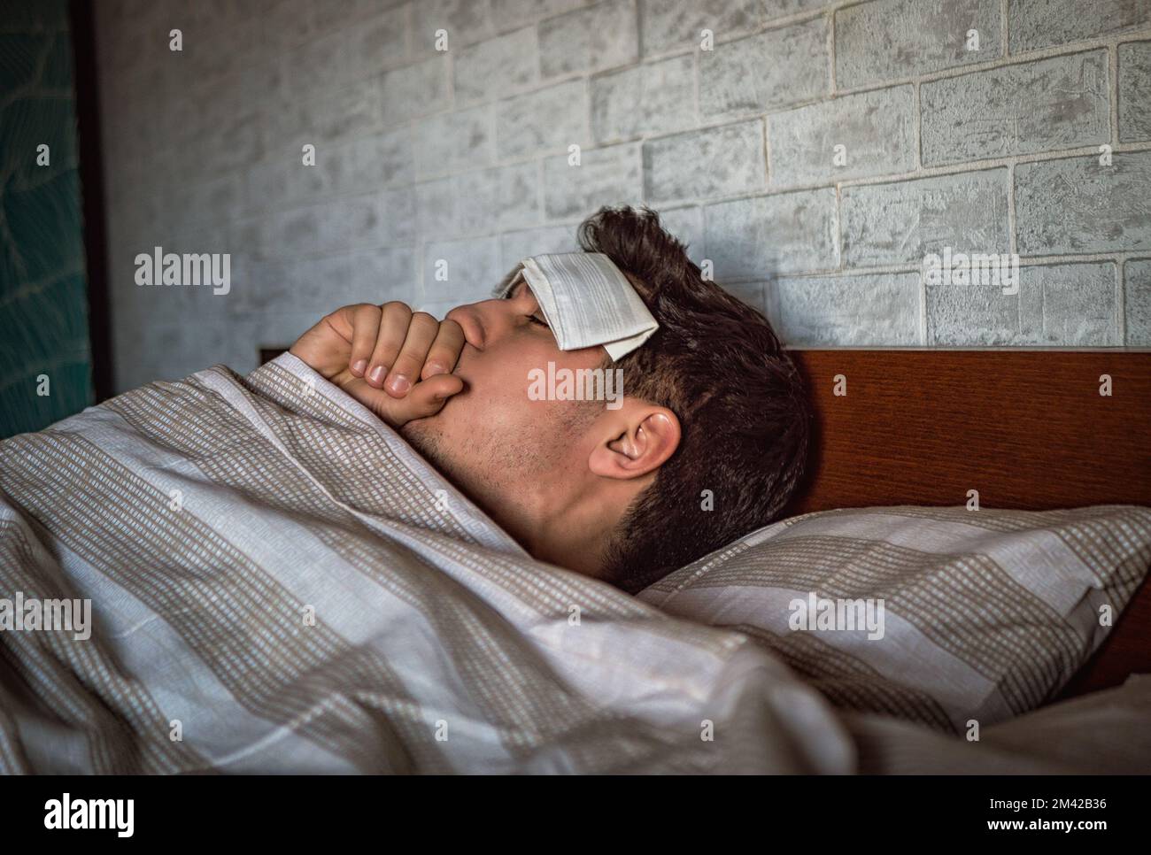 Young handsome sick or unwell man in bed with a flu or fever Stock Photo