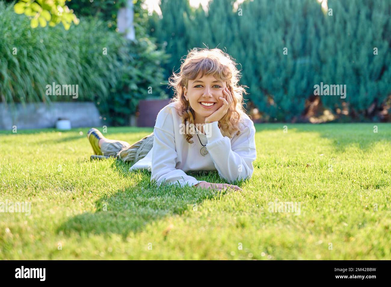 Portrait of cute teenage girl lying on grass looking at camera Stock ...