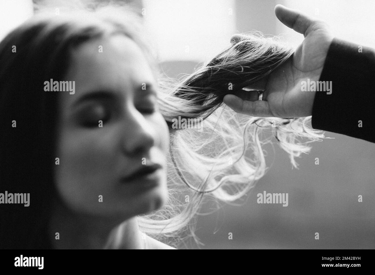 the girl closed her eyes, and the guy's hand holds her lock of hair