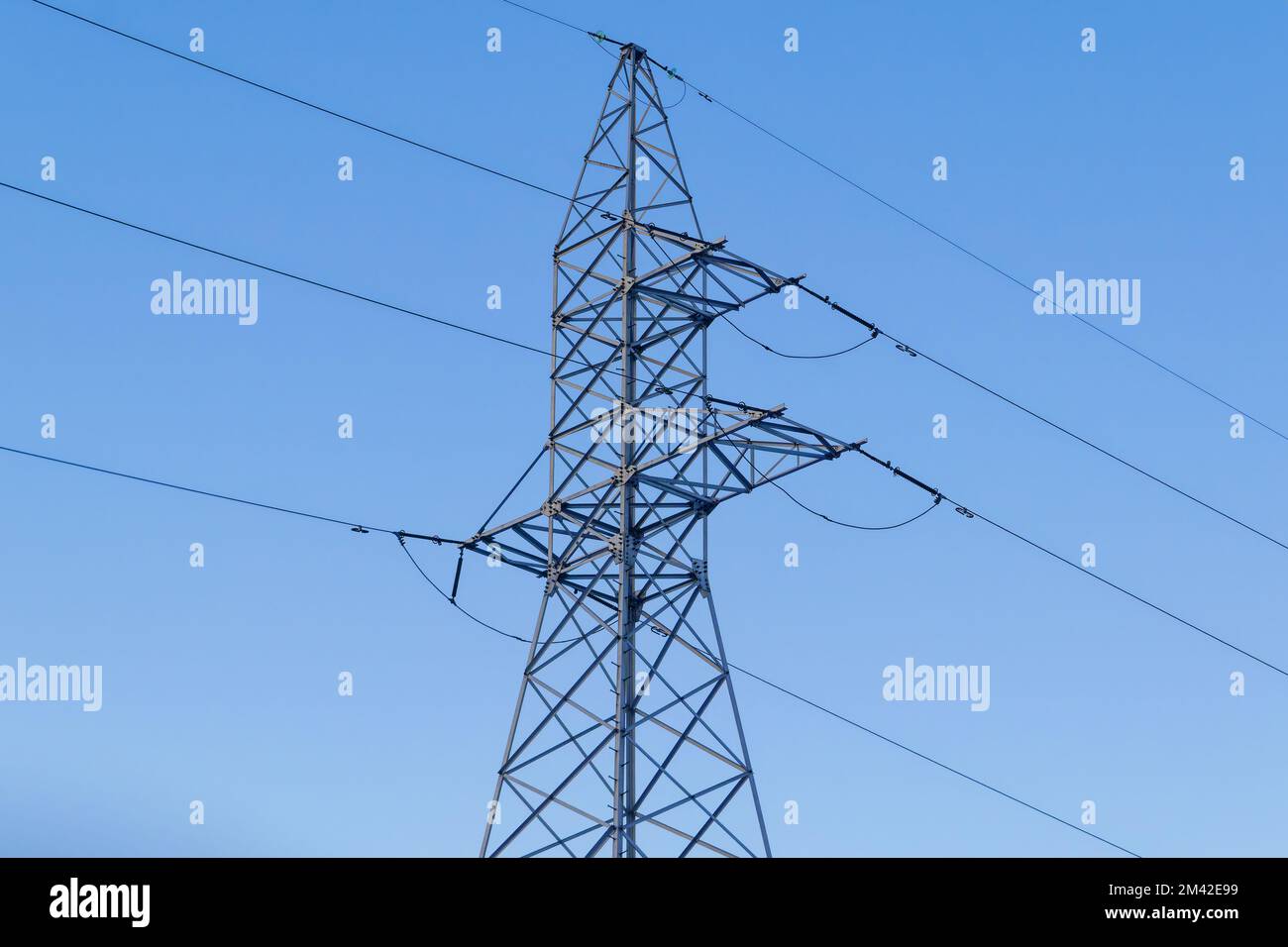 High voltage power pylons against blue sky and sun rays Stock Photo - Alamy
