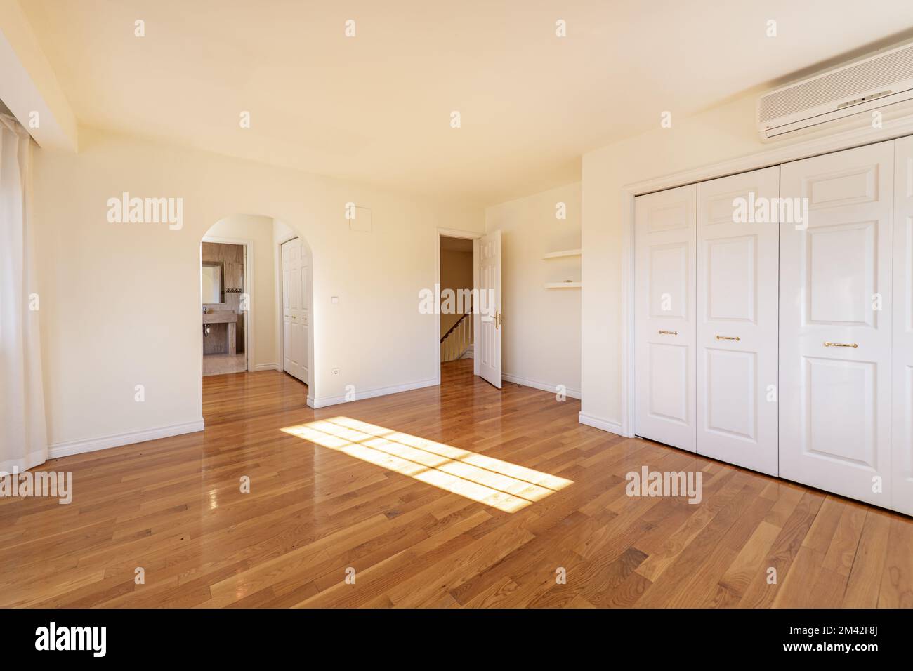 Large bedroom with built-in wardrobes, walk-in closet leading to an en-suite bathroom in a two-story detached house Stock Photo