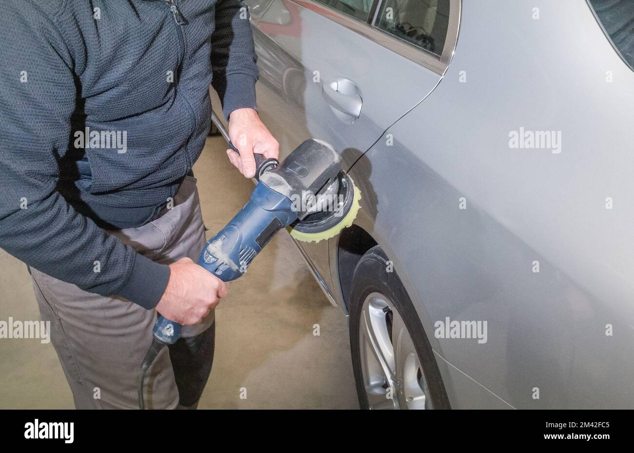 Polishing the car. Car service worker with electrical polisher