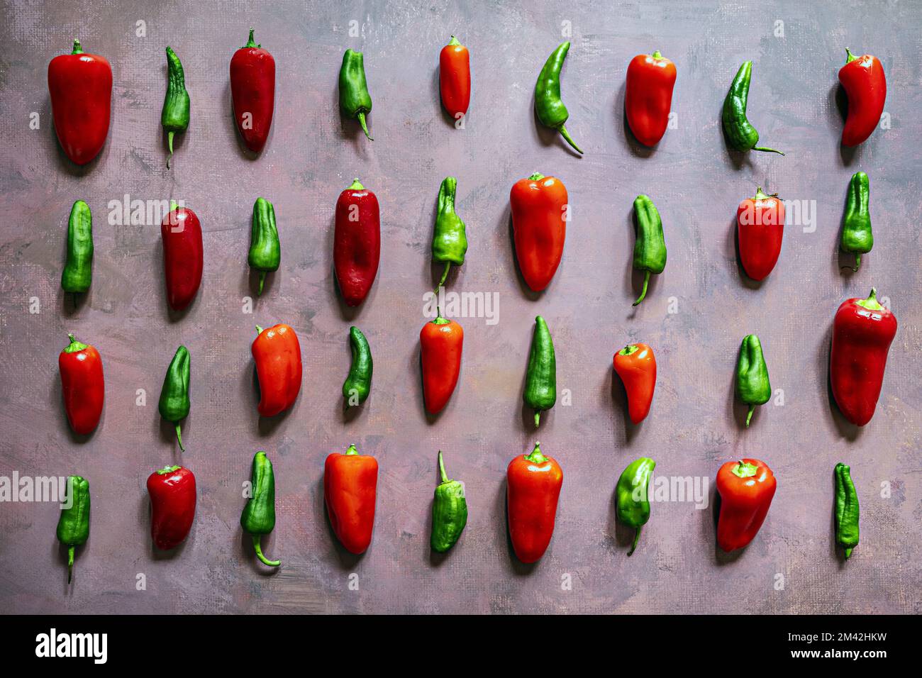 Rows of red and green bell peppers on a dirty pink background Stock ...