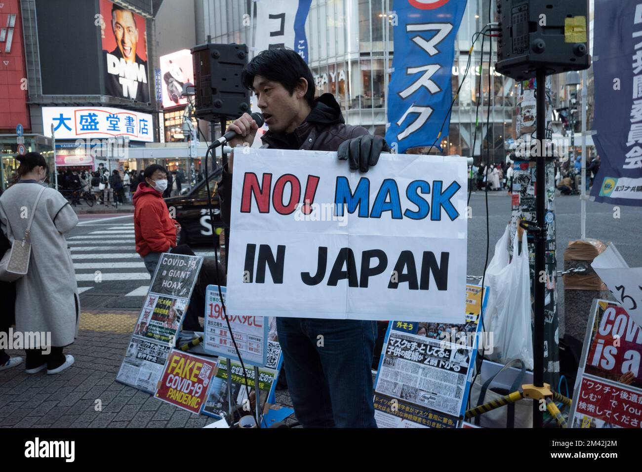 Tokyo, Japan. 18th Dec, 2022. Anti-Mask protesters hold a demonstration at a corner along the Shibuya Scramble pedestrian intersection trying to convince locals and tourists to not wear masks. Despite not having any government public health mandate requiring masks, most Japanese residents have continued to wear masks in public throughout the entire COVID-19 pandemic and continue to do so today. The demonstrators insist the virus is not as deadly as its put out to be by the media and insist the response to the pandemic is a hoax to exert control over the general public.Japan has recently r Stock Photo