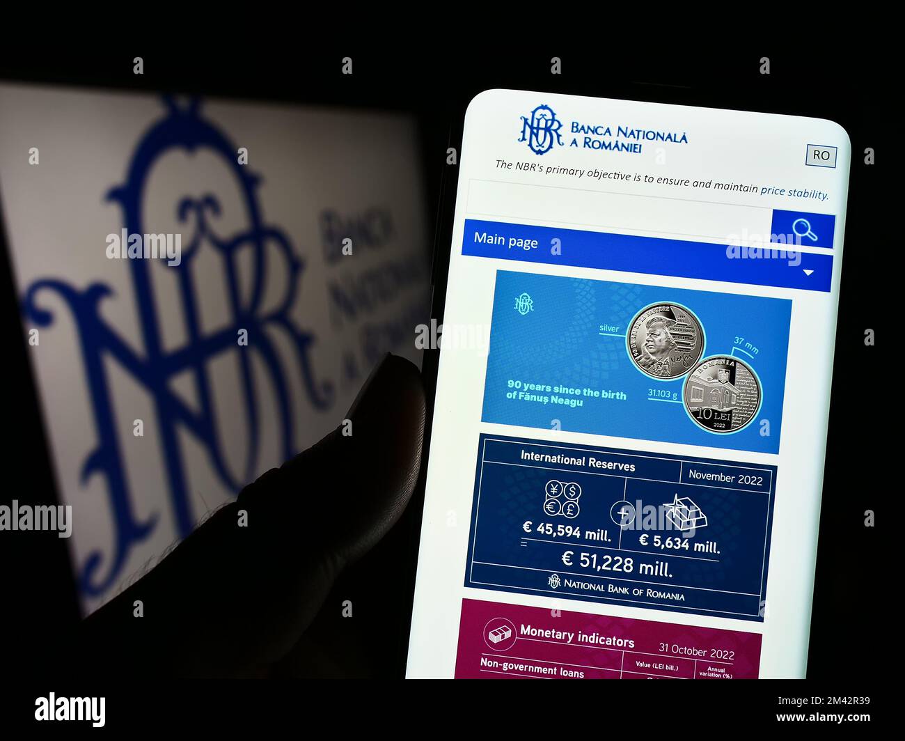 Person holding cellphone with website of central bank Banca Nationala a Romaniei (BNR) on screen with logo. Focus on center of phone display. Stock Photo