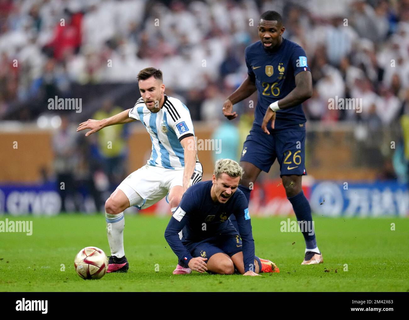France's Antoine Griezmann (centre) goes down whilst battling for the ball against Argentina's Nicolas Tagliafico (left) during the FIFA World Cup final at Lusail Stadium, Qatar. Picture date: Sunday December 18, 2022. Stock Photo
