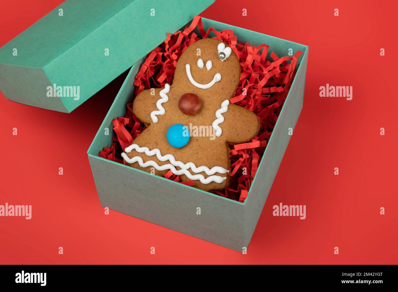 Christmas gingerbread man cookie in green box and on red background, surprise cookies in gift box Stock Photo