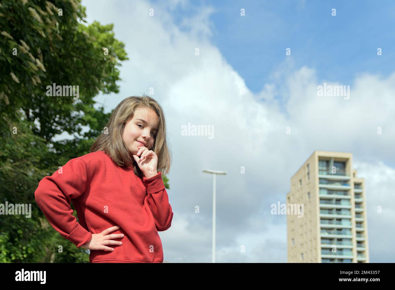 Children in the city. Portrait of a teenage girl on the background of the city and the blue sky. Stock Photo