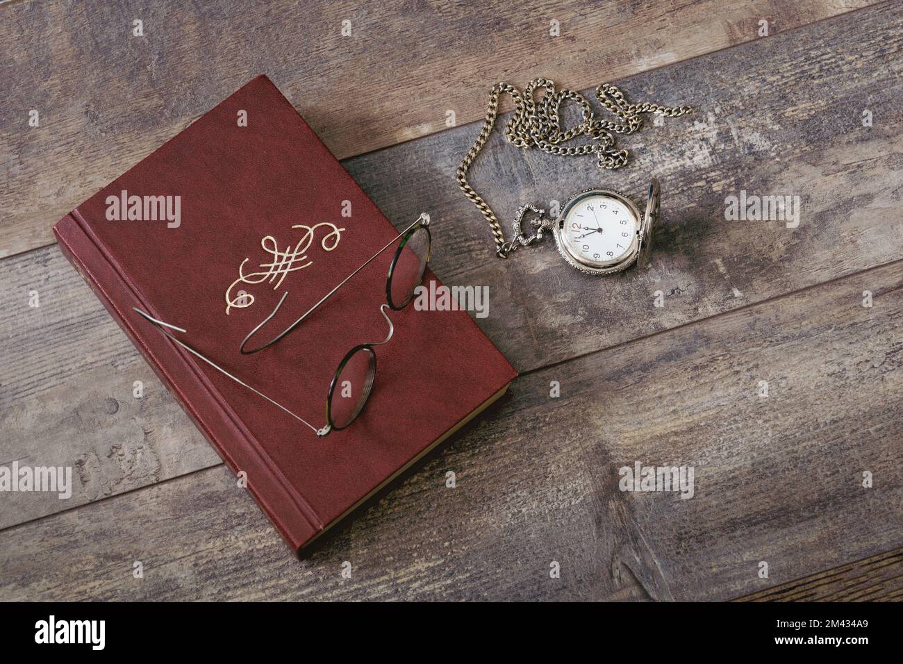 Old book, glasses and pocket watch on a textured table. Old fashioned still life Stock Photo