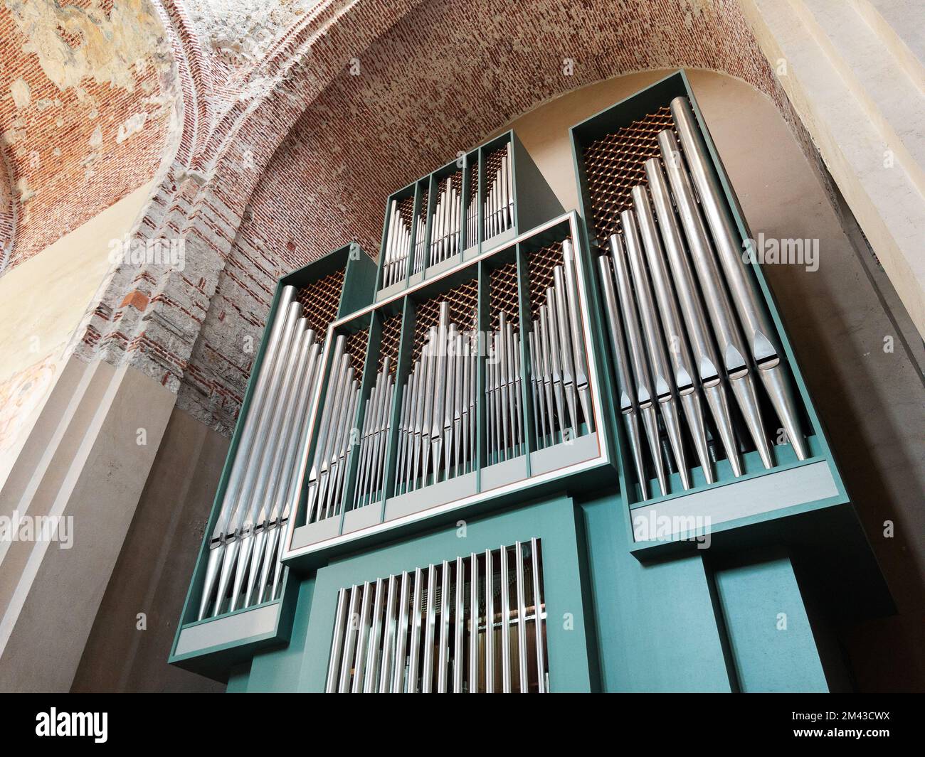 An ancient musical instrument, a blue-colored organ in a church with a construction of vertical pipes Stock Photo