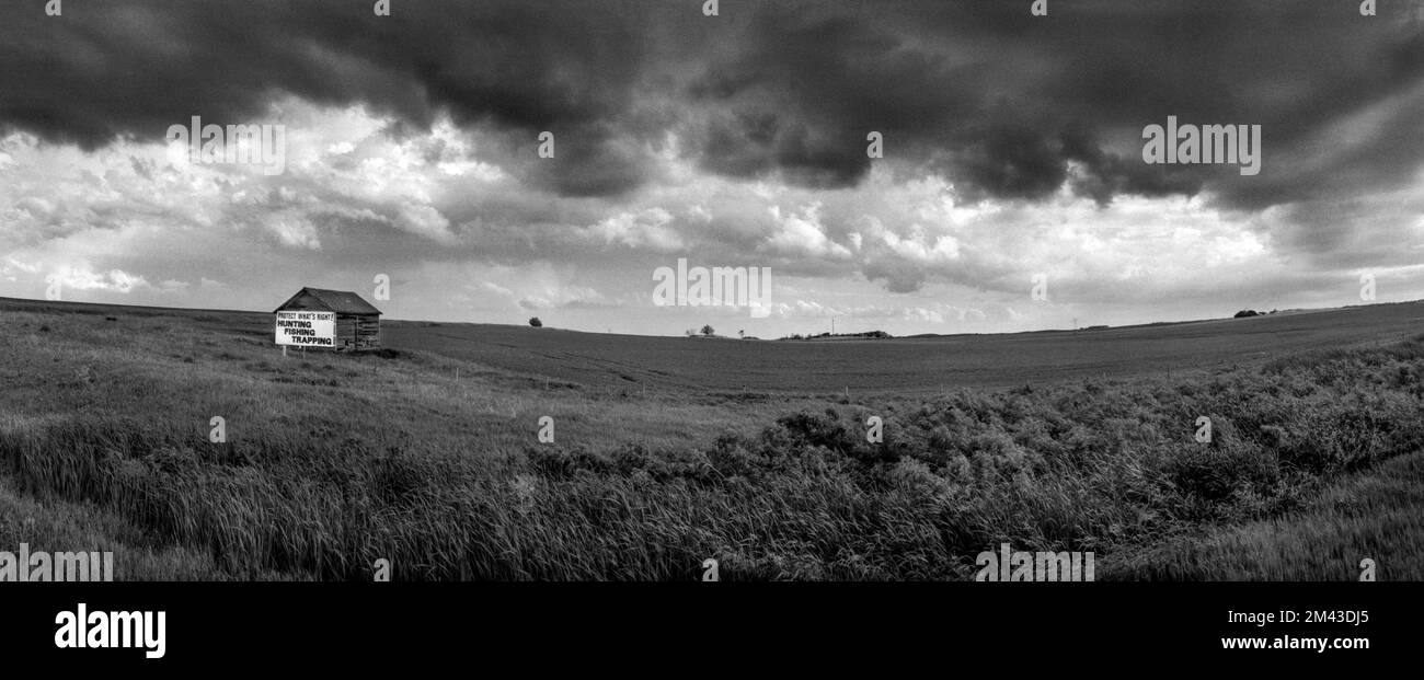 Panorama landscape with storm clouds and a farm building with a sign, “Protect What's Right, Hunting, Fishing, Trapping” in Barnes County, ND Stock Photo