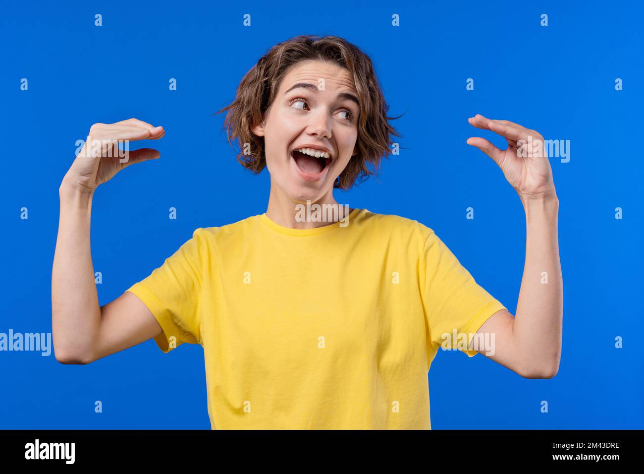 Funny woman showing bla-bla-bla gesture with hands on blue background. Empty promises, irony, blah concept. Lier. Stock Photo