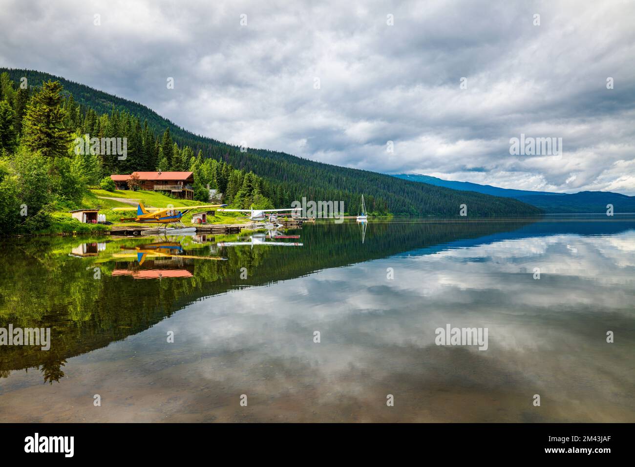 Float planes; still water reflects dramatic clouds; Dease Lake; British