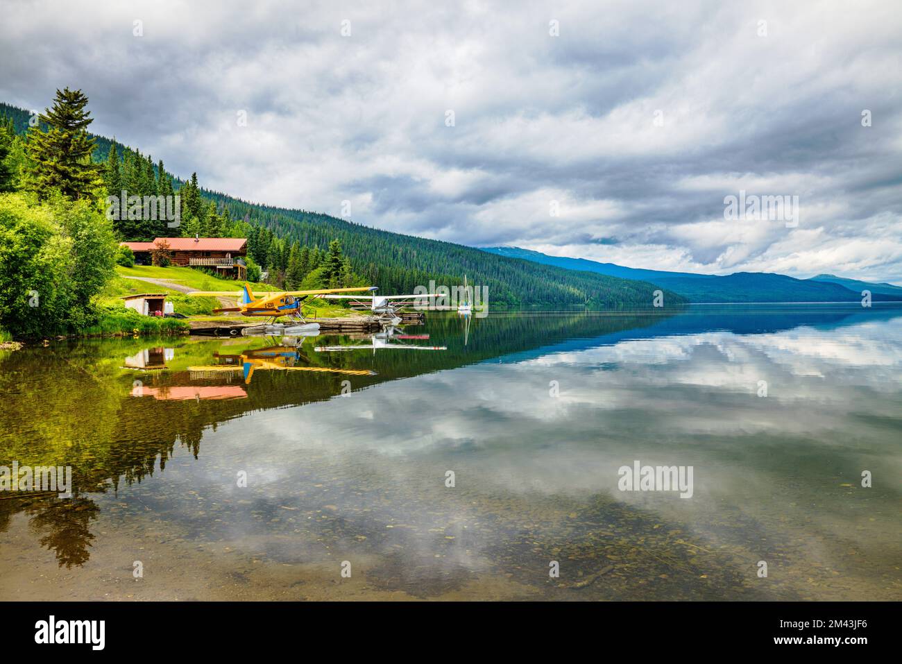 Float planes; still water reflects dramatic clouds; Dease Lake; British