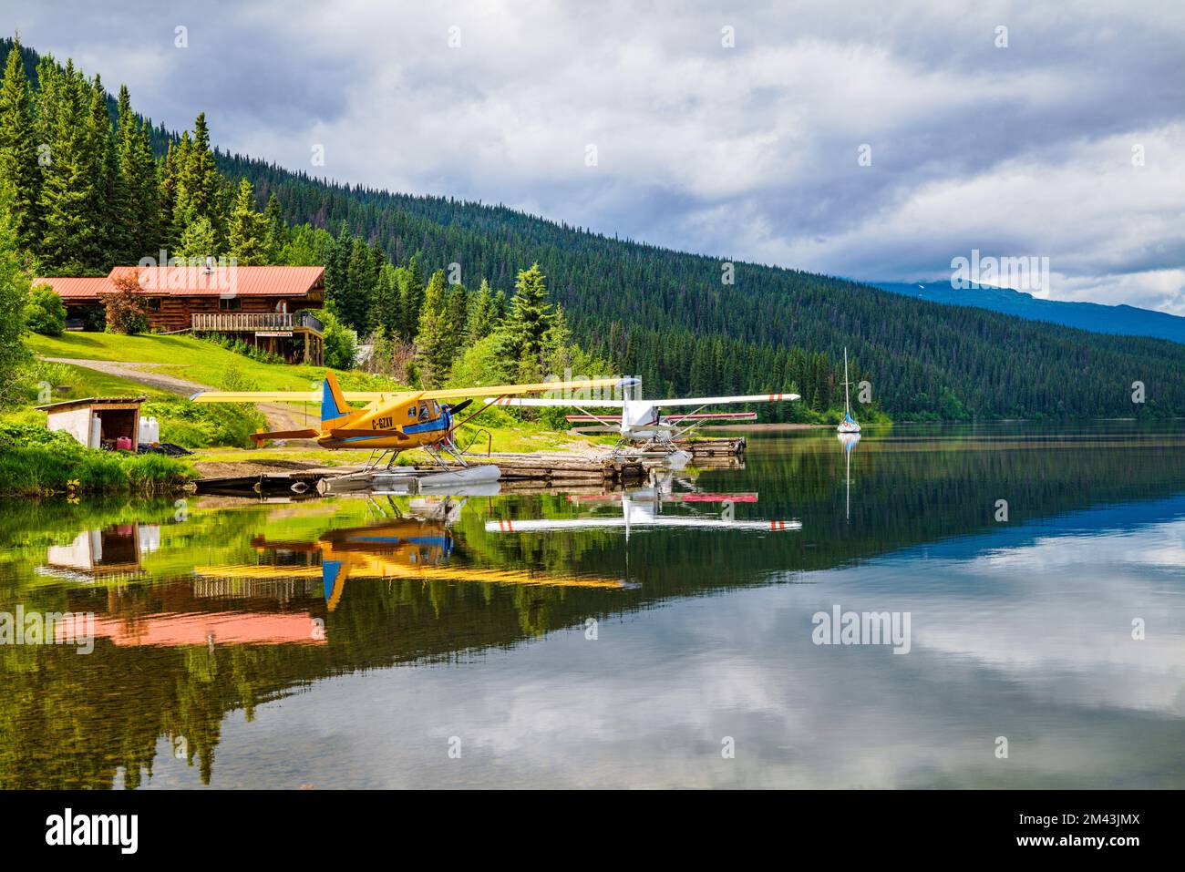 Float planes; still water reflects dramatic clouds; Dease Lake; British