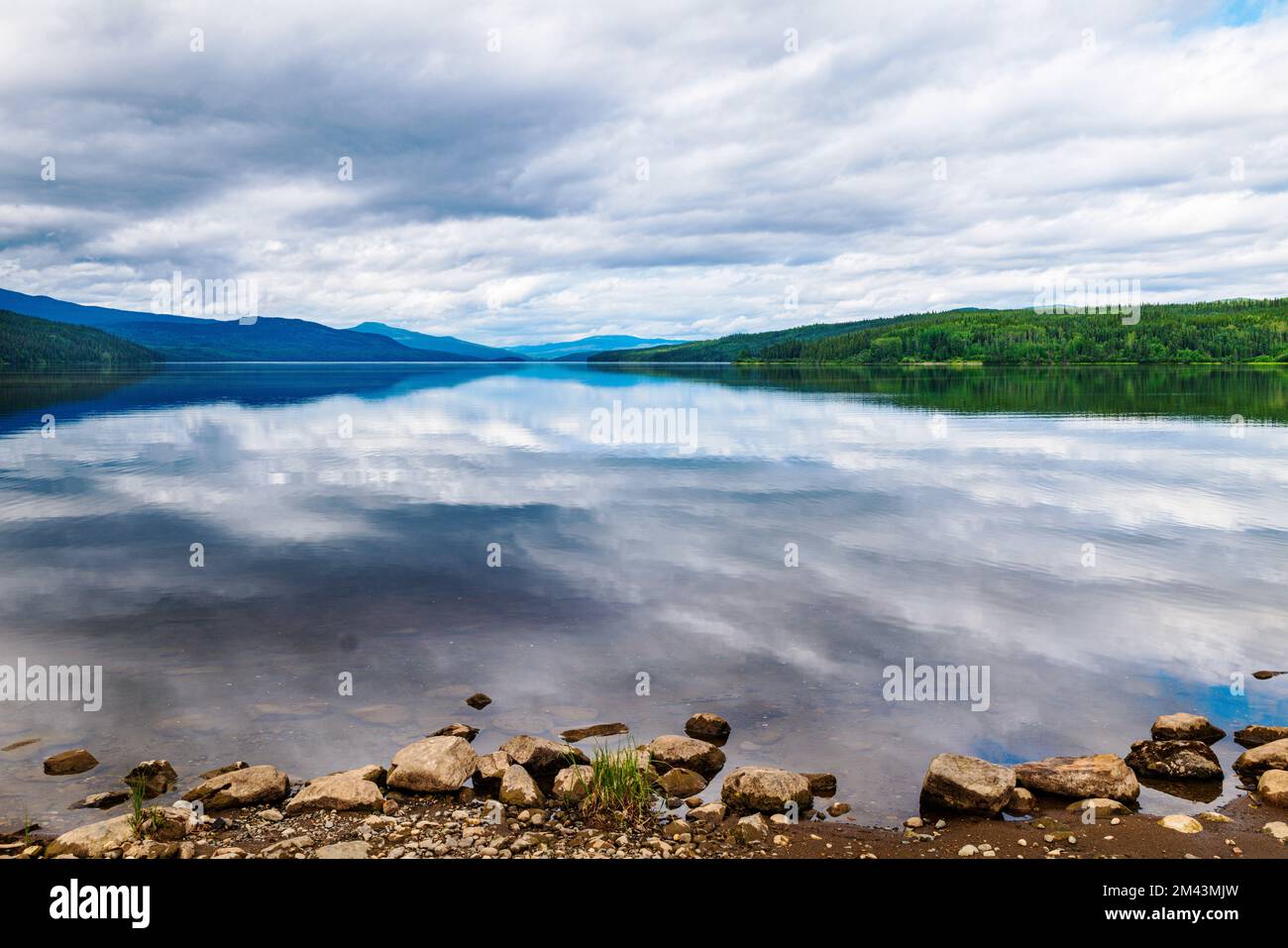 Still water reflects dramatic clouds; Dease Lake; British Columbia