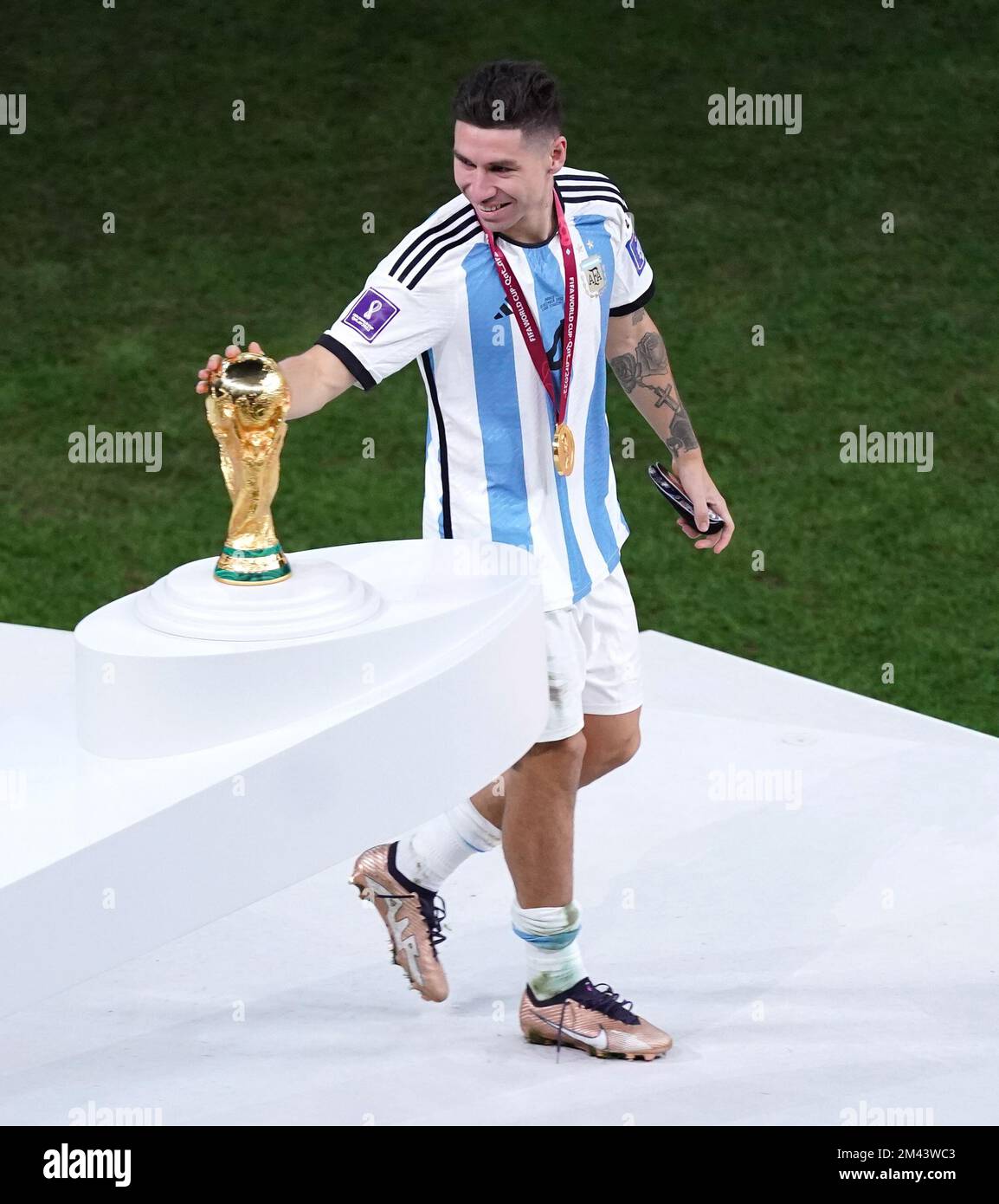 Argentina's Enzo Fernandez walks past The World Cup Trophy after