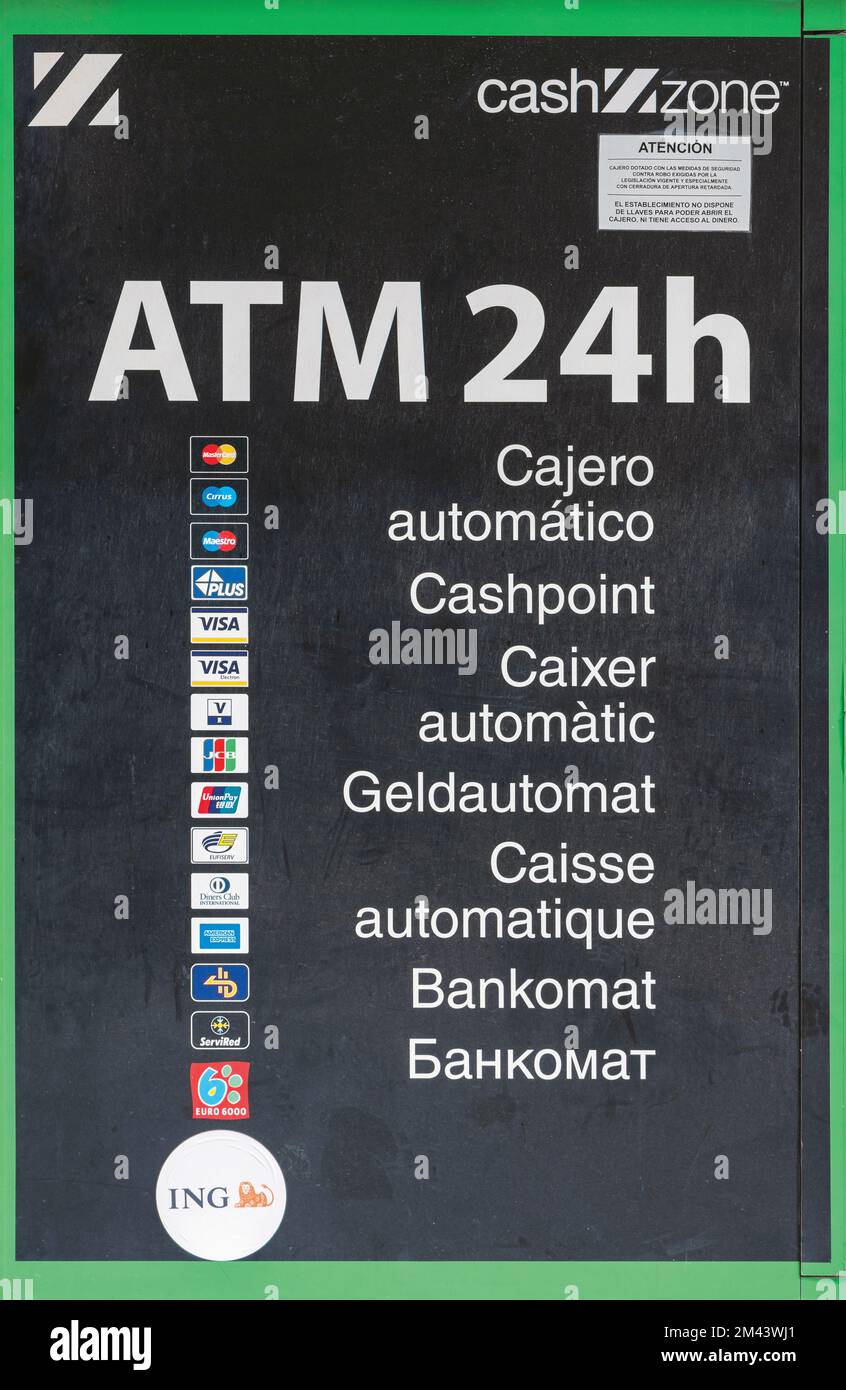 A 24 hour ATM machine advertising itself in 7 languages, Marbella, Costa del Sol, Malaga Province, Spain.  From the top the languages are Spanish, Eng Stock Photo