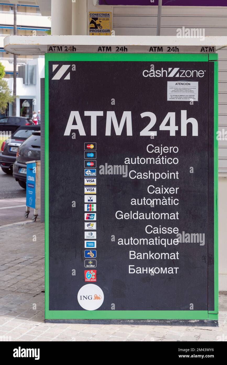 A 24 hour ATM machine advertising itself in 7 languages, Marbella, Costa del Sol, Malaga Province, Spain.  From the top the languages are Spanish, Eng Stock Photo