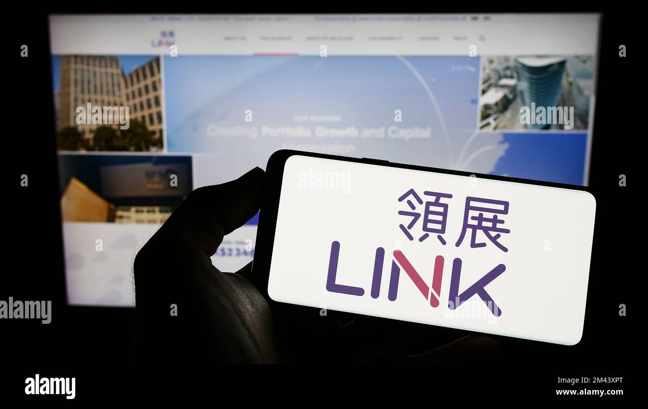 Person holding cellphone with logo of company Link Real Estate Investment Trust on screen in Person holding cellphone with logo of company Link Real Estate Investment Trust on screen in