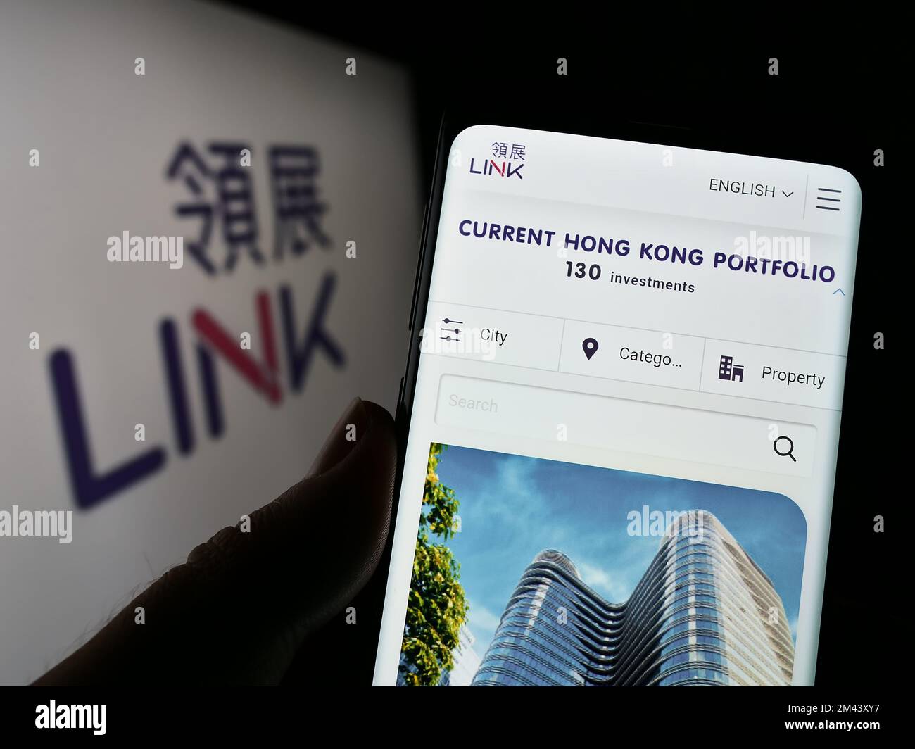 Person holding cellphone with webpage of company Link Real Estate