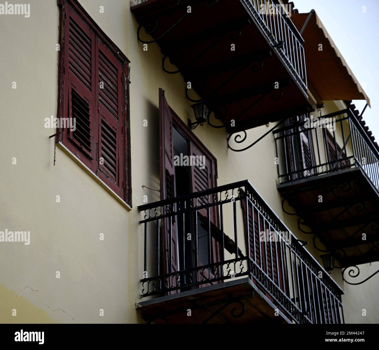 Old rural house facade with wooden window shutters and a balcony with ...