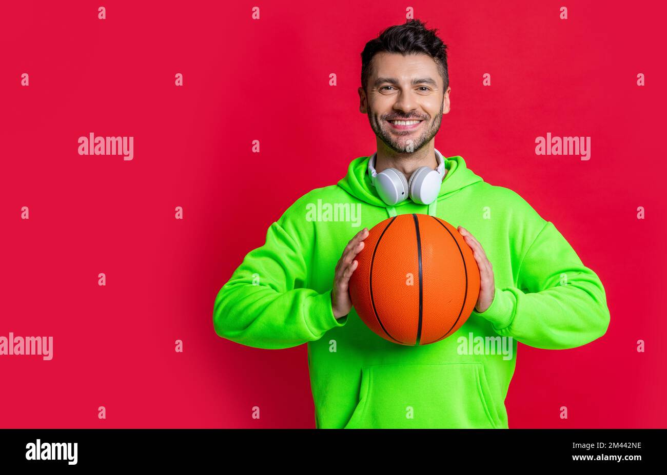 smiling man holding basketball ball studio. Basketball player smiling  isolated on red Stock Photo - Alamy