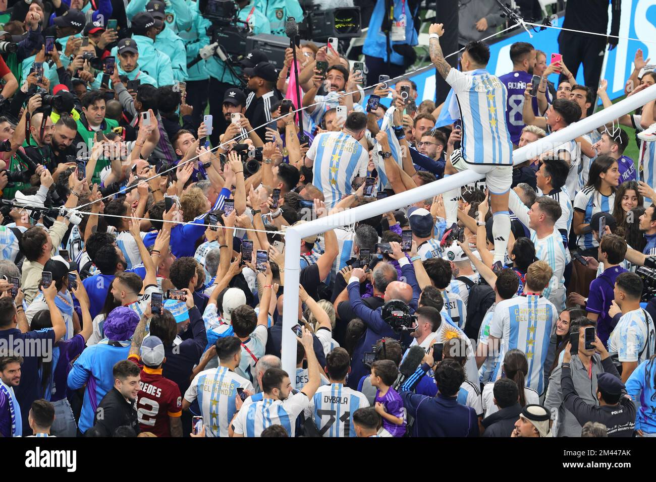Lusail, Qatar. 18th Dec, 2022. Lionel Messi of Argentina under the goal  posts with trophy is swamped by everyone during the Final of the FIFA World  Cup Qatar 2022 between Argentina and