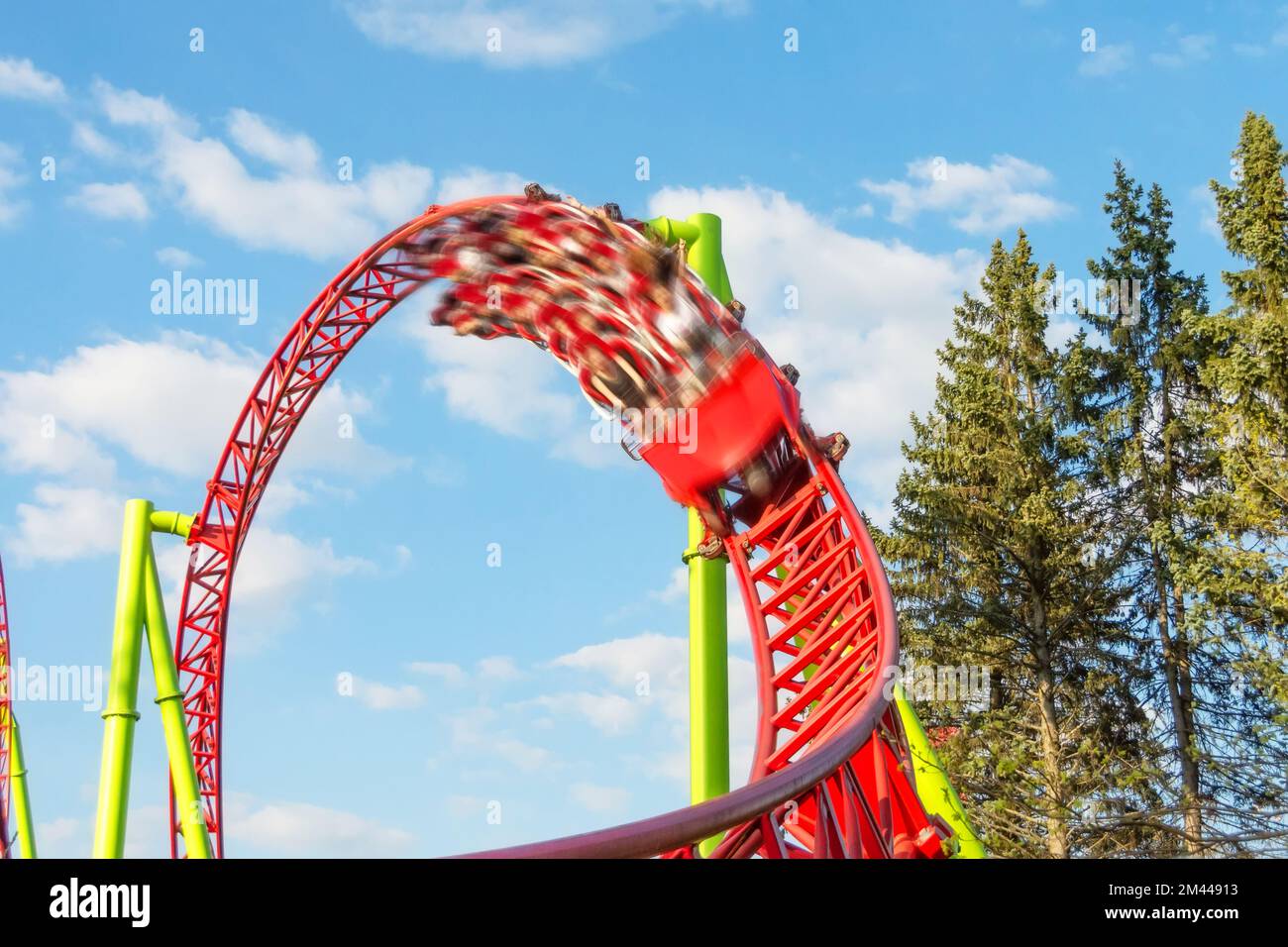 Amusement cart makes circular loops upside down and turns sharply out of the loop with motion blur effect, a roller coaster Stock Photo