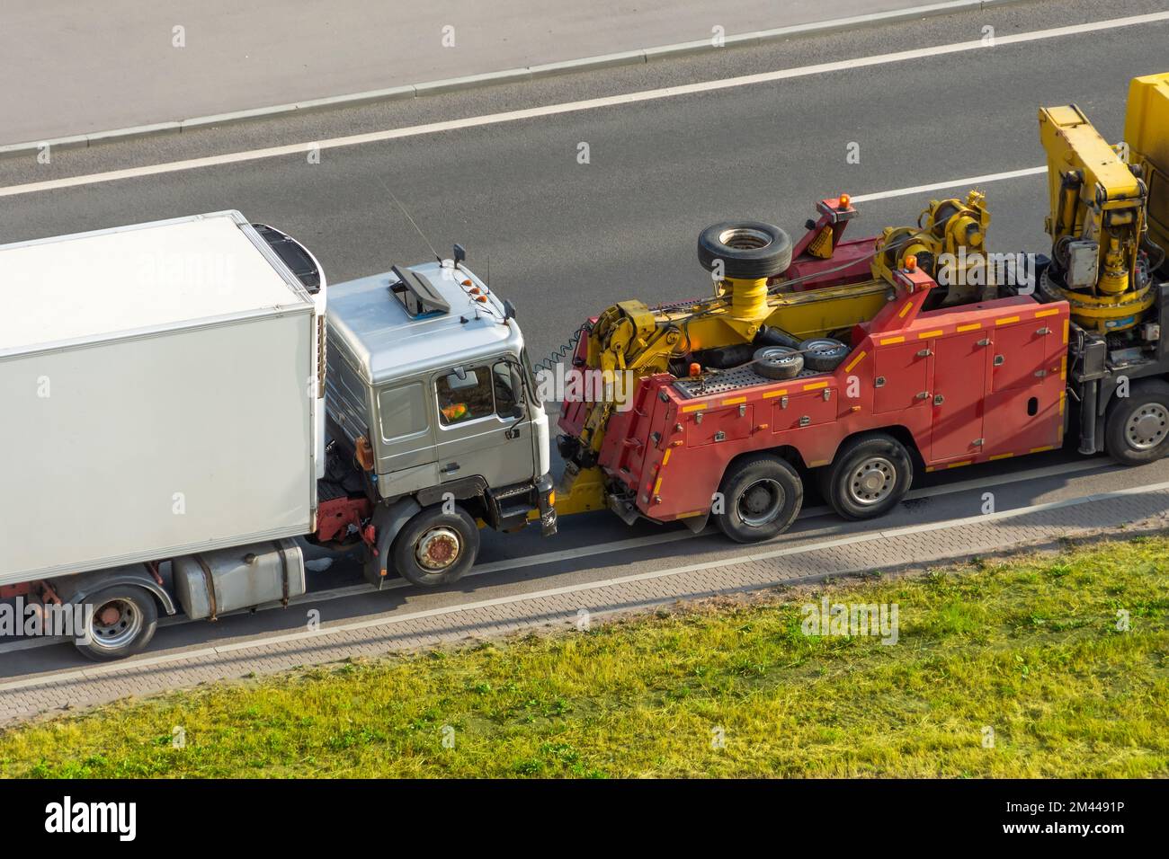 Powerful heavy duty big rig mobile tow semi truck emergency lights and towing equipment prepare tow broken white semi tractor standing out service hig Stock Photo