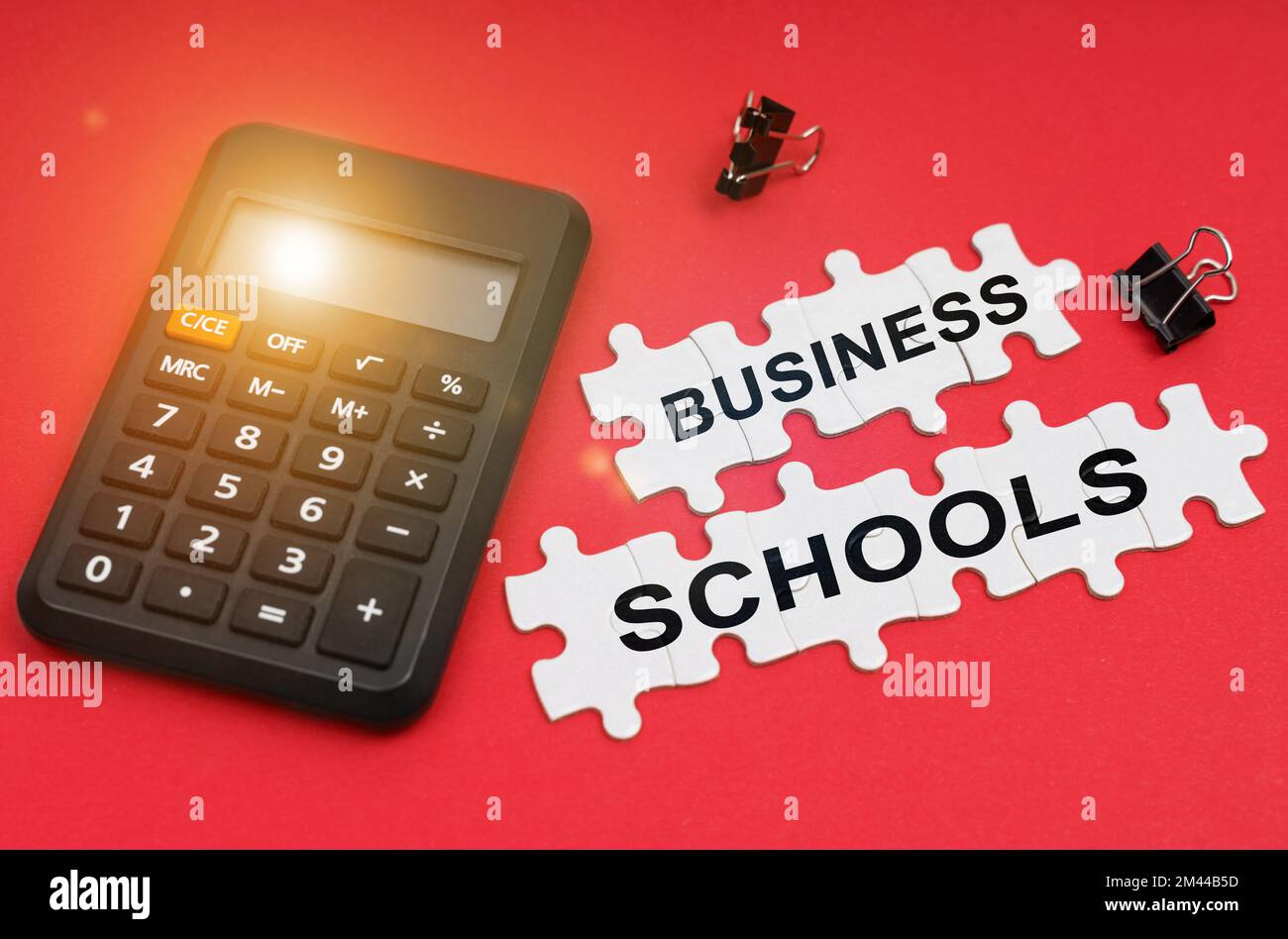 Finance and economy concept. On the red surface are a calculator, clamps and puzzles with the inscription - Business Schools Stock Photo