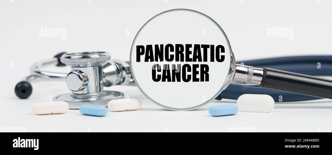 Medicine and health concept. On a white surface are pills, a stethoscope and a magnifying glass inside which is written - Pancreatic cancer Stock Photo