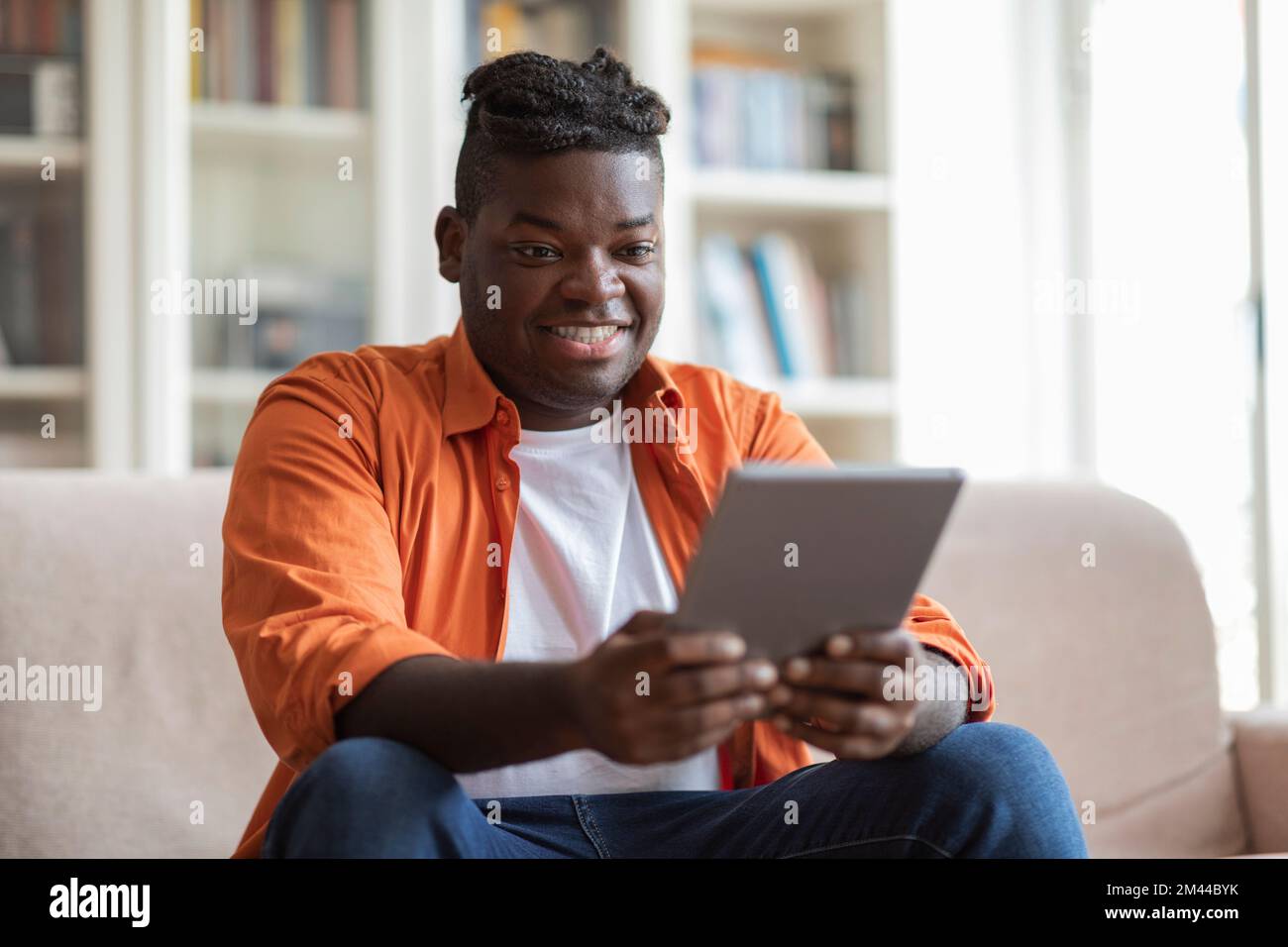 Positive cool black guy using digital tablet at home Stock Photo