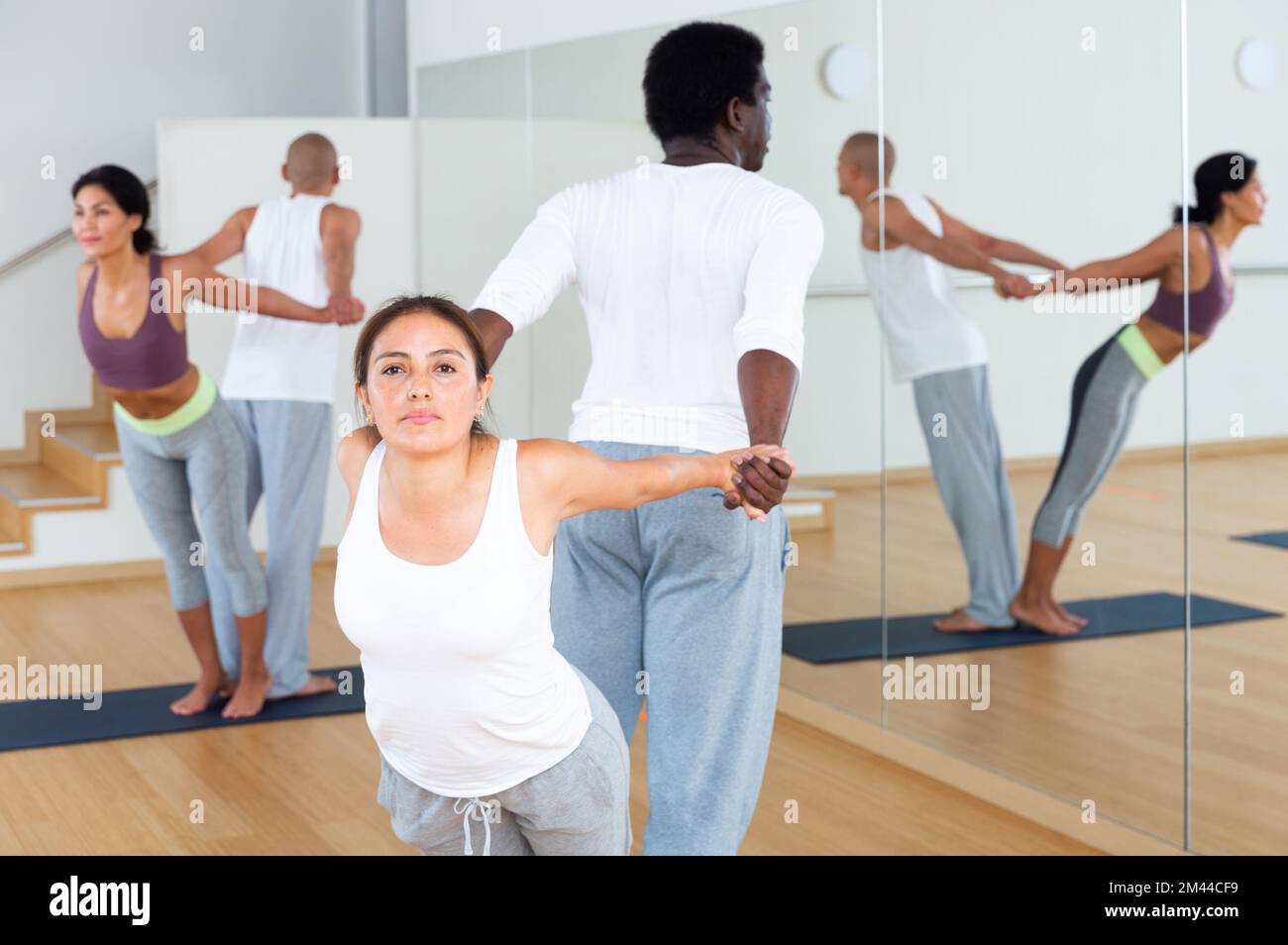 Couples practicing yoga with partner at studio Stock Photo