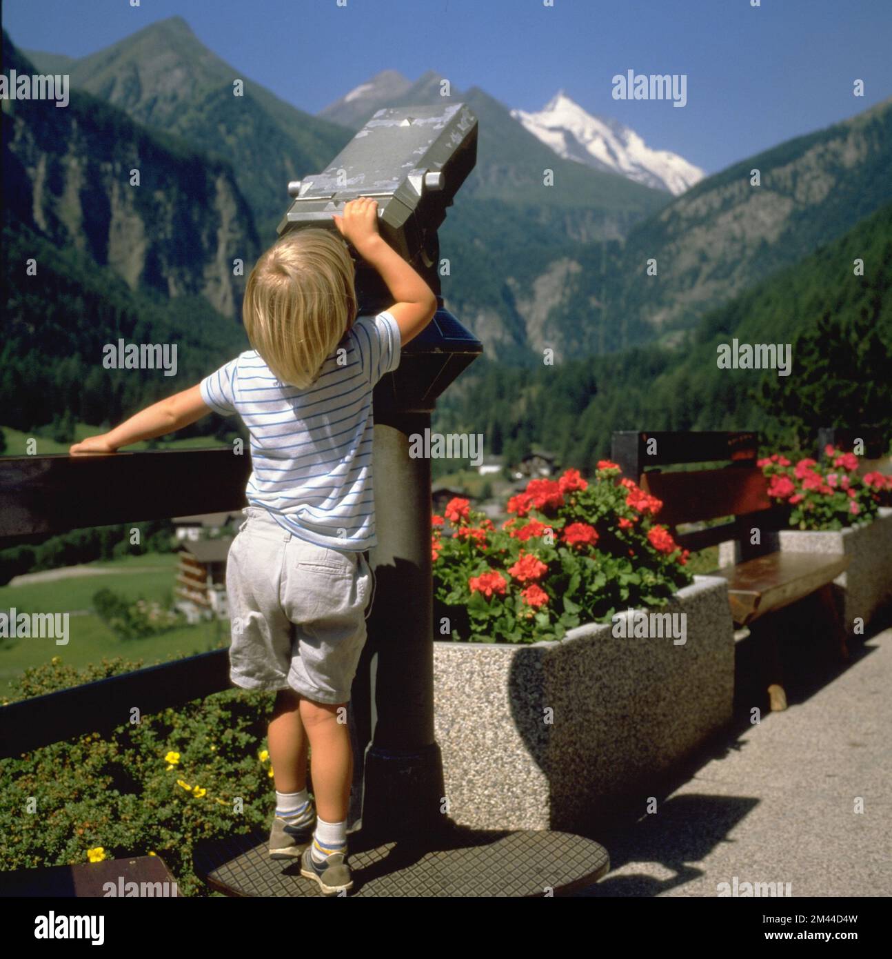 Kind schaut durch Fernrohr auf die Berge Stock Photo