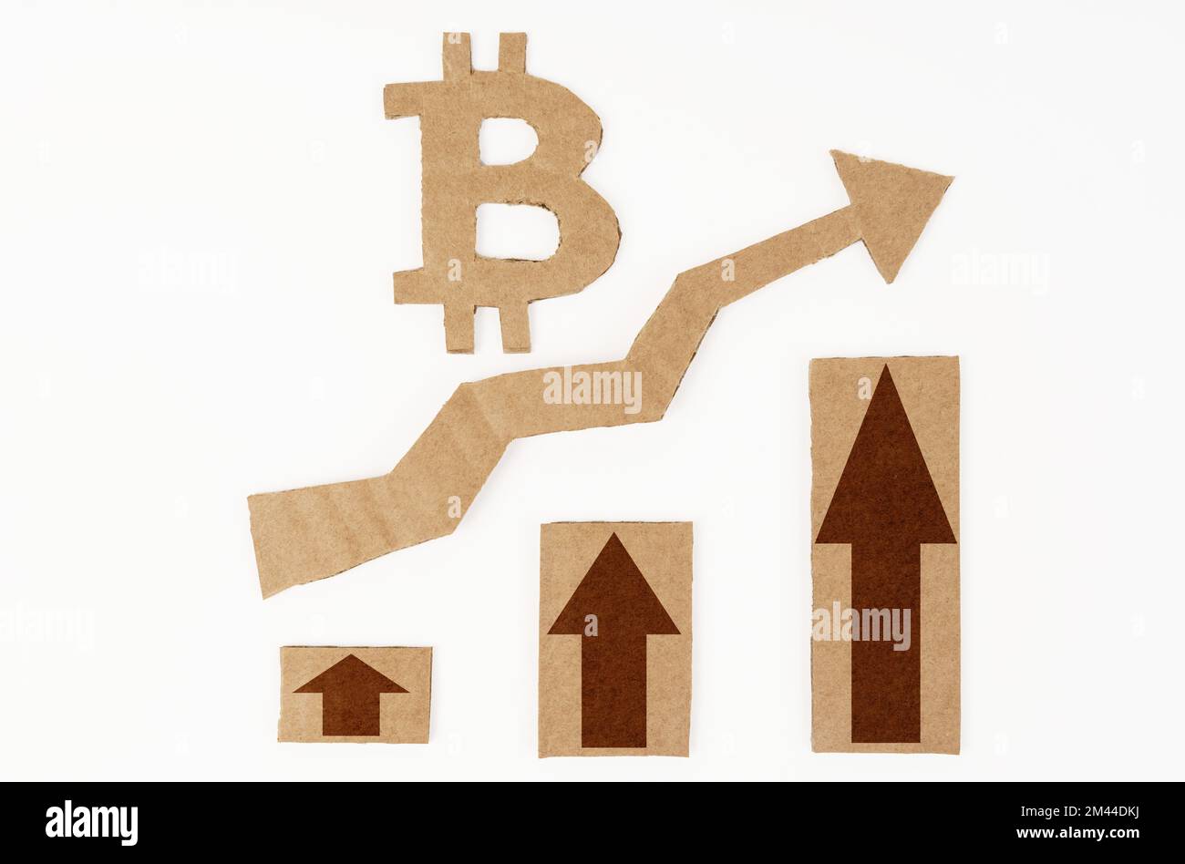 The concept of economic growth. On a white surface, a graph with up arrows and a bitcoin symbol. Symbol, arrow and graph are made of cardboard Stock Photo