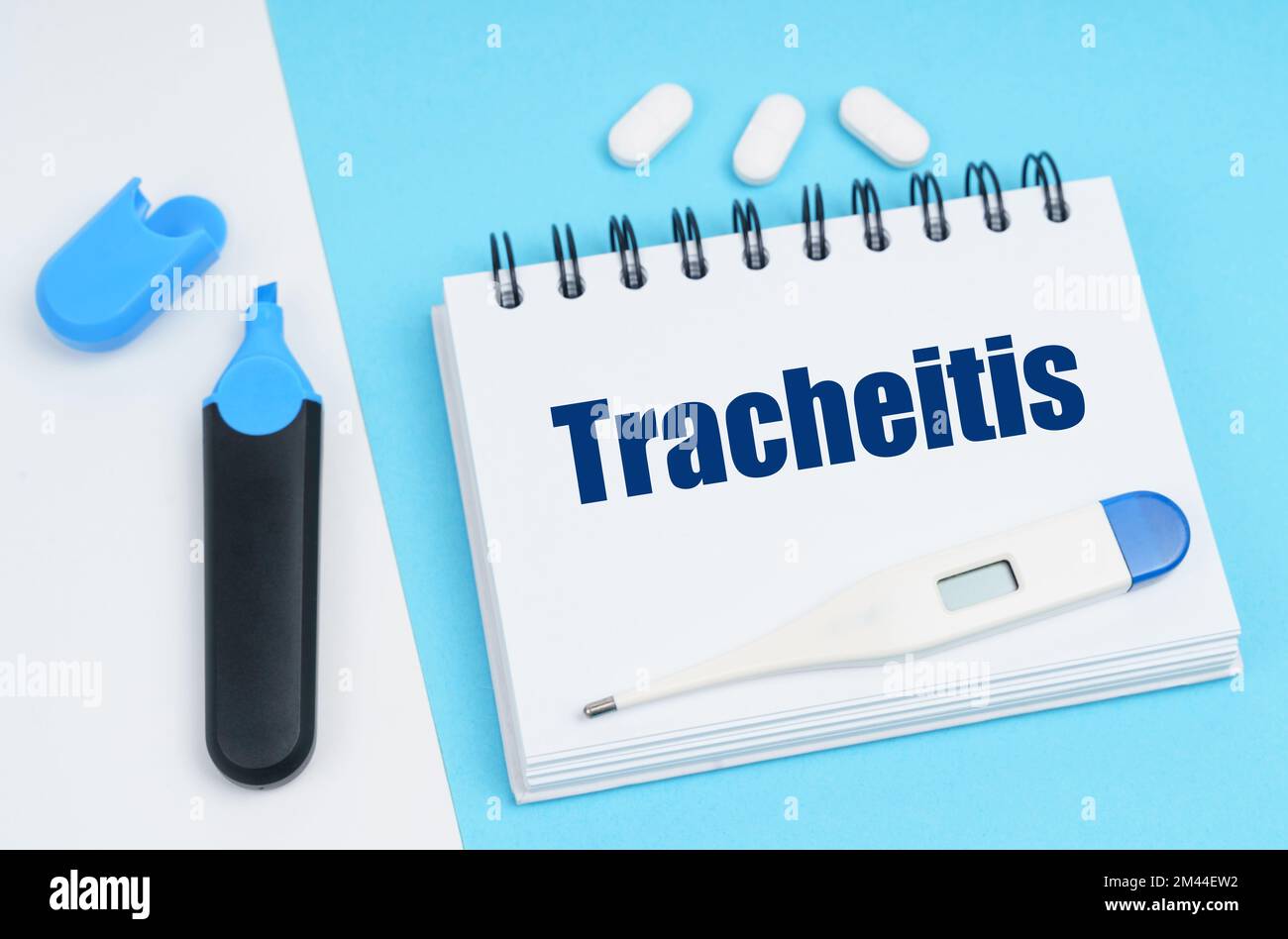 Medical diagnosis concept. On a white-blue surface are pills, a thermometer, a marker and a notebook with the inscription - Tracheitis Stock Photo