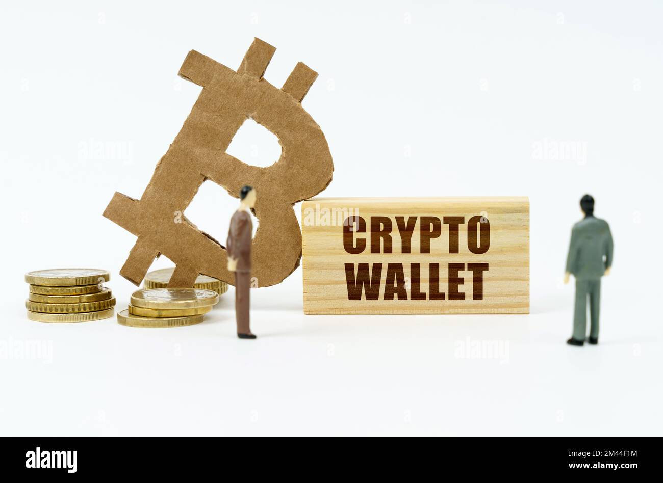 Cryptocurrency and business concept. On the white surface of the coin, the bitcoin symbol, miniature figures of businessmen and a wooden plate with th Stock Photo