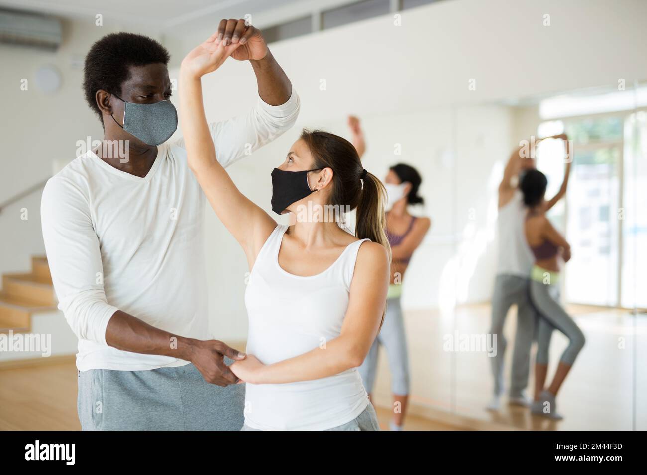 Group of multinational people in protective masks practicing dance techniques Stock Photo
