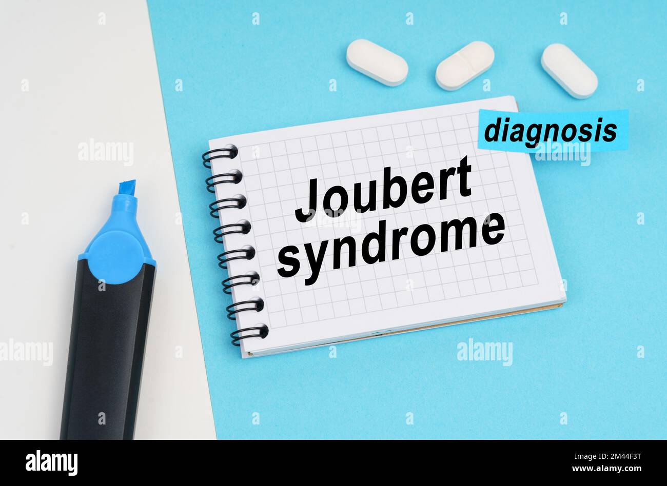 Medicine and health concept. On a white and blue surface are pills, a marker and a notebook with the inscription - Joubert syndrome, a sticker with th Stock Photo