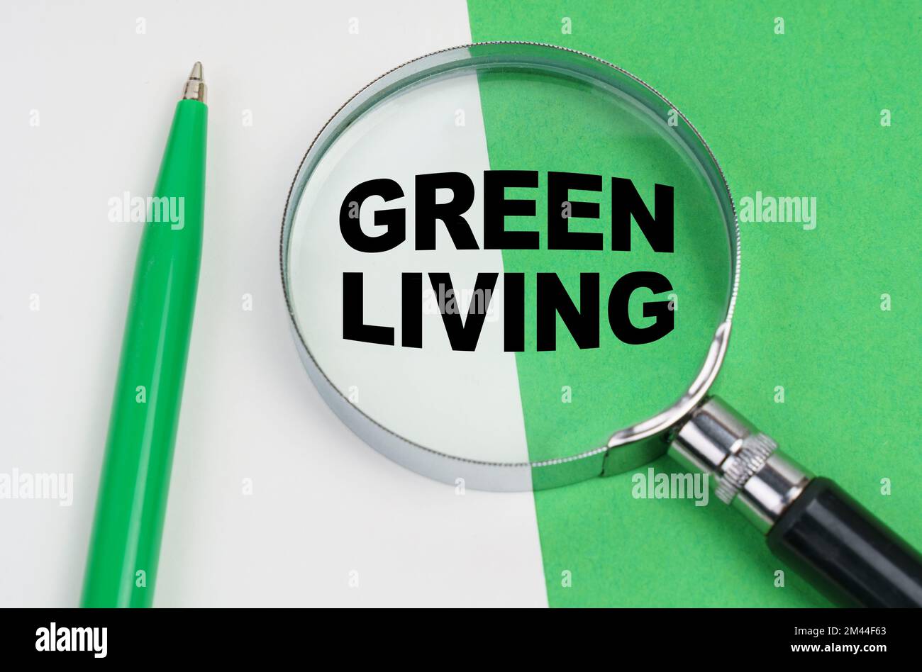 Ecological concept. On a white-green background lies a pen and a magnifying glass, inside which is the inscription - Green Living Stock Photo