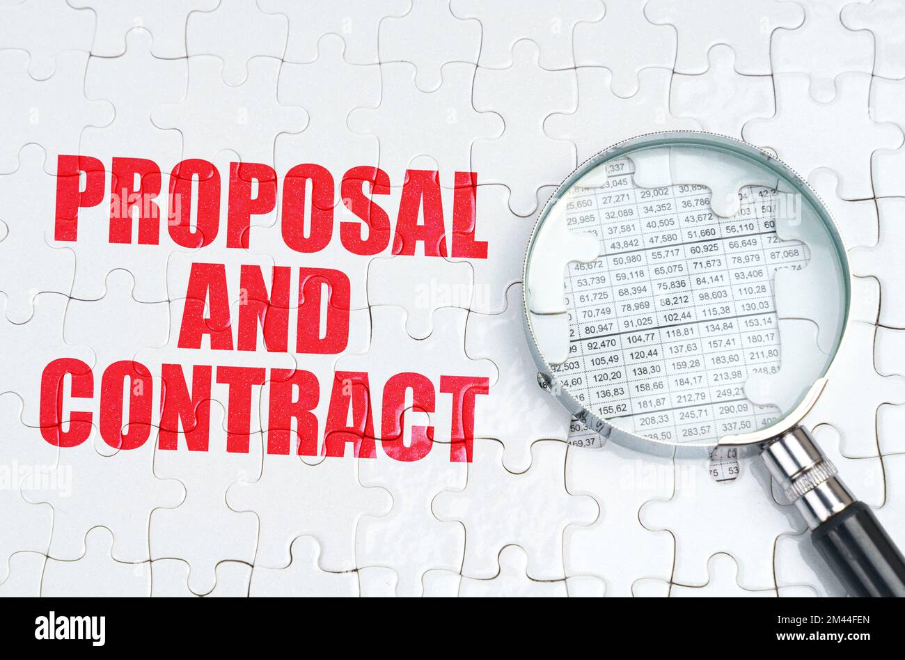 Business concept. There is a magnifying glass on the puzzles, next to it is written - Proposal and contract Stock Photo