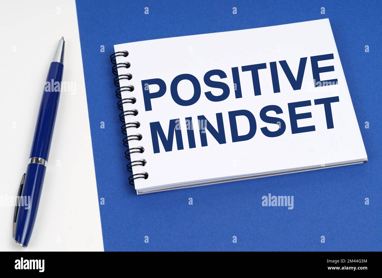 Business and finance concept. On a blue-white surface lies a pen and a notebook with the inscription - Positive Mindset Stock Photo