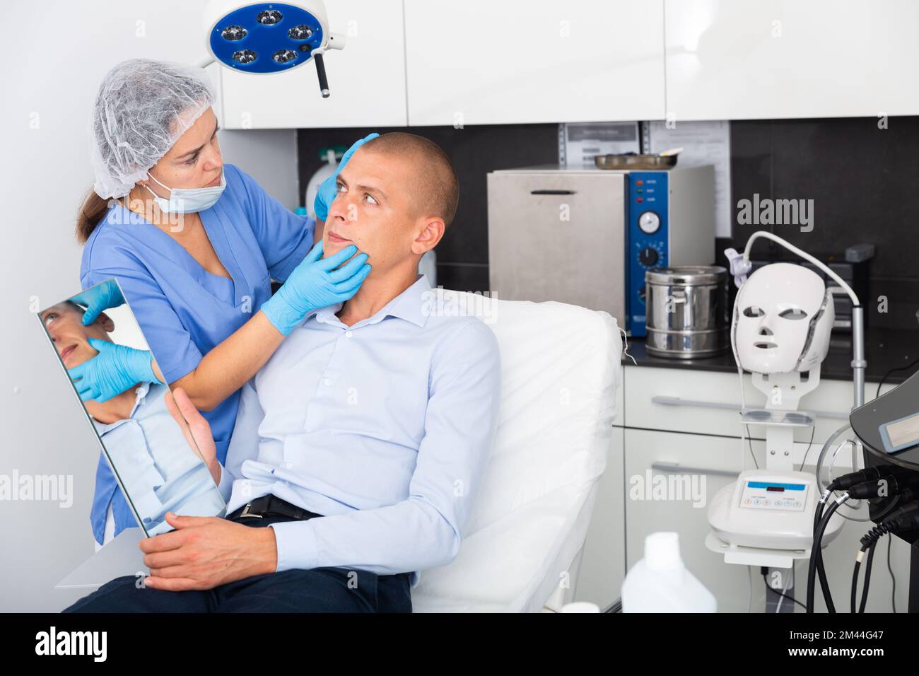 Female cosmetician explaining man hardware facial procedure in ...