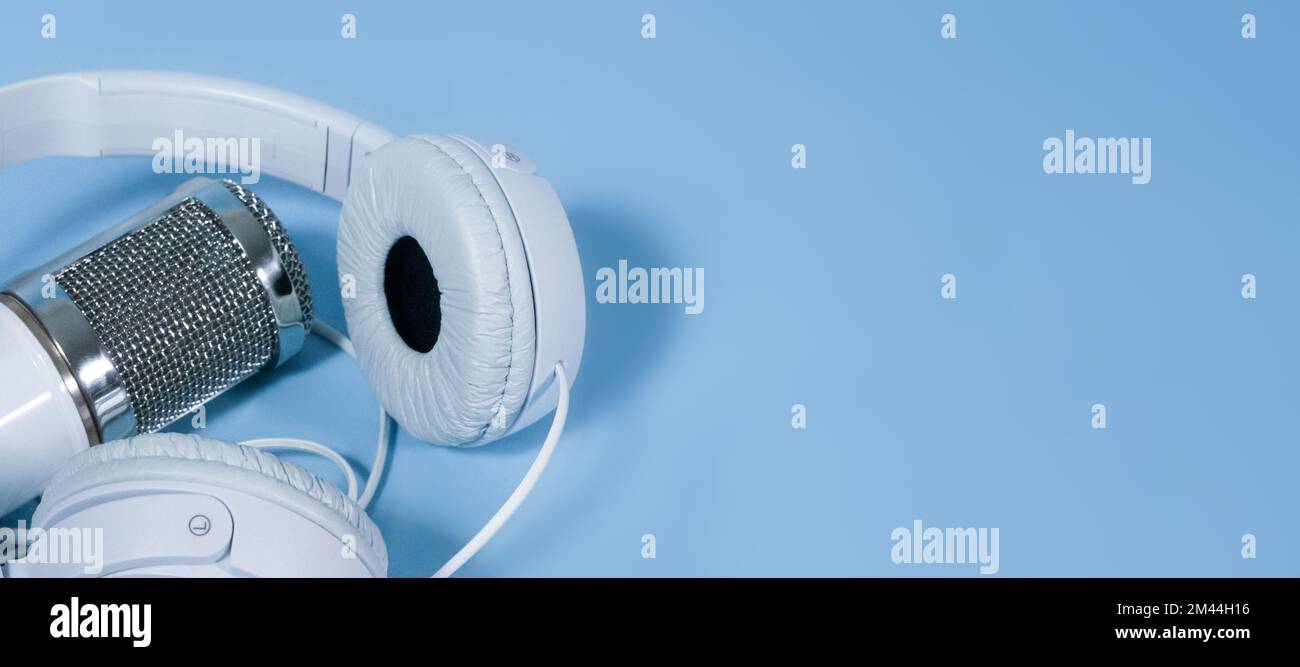 White headphones and microphone for sound recording on a blue background Stock Photo