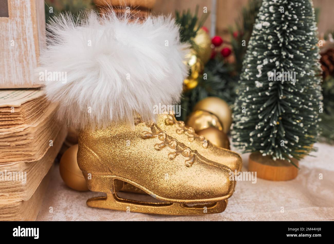 Two figure ice skates Christmas decor. Pair of golden skate shoes with fir. Vintage wintertime holidays. Skates on the top of fireplace. Christmas dec Stock Photo