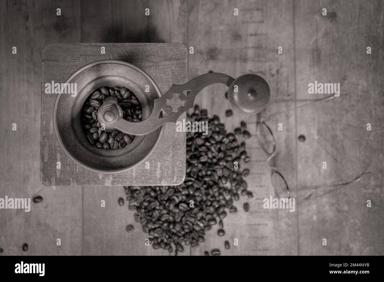 Old manual coffee grinder. Coffee beans scattered on a textured table and old glasses for composition Stock Photo